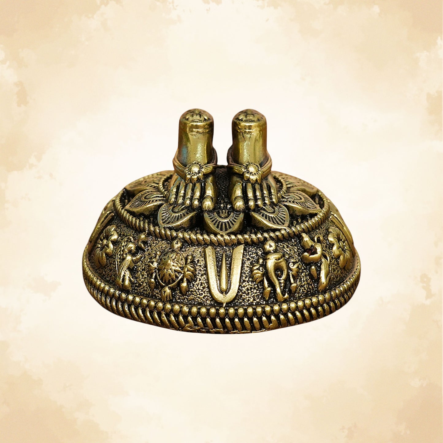 Handcrafted brass Charan Paduka placed on an ornate circular base with elephant and floral carvings.