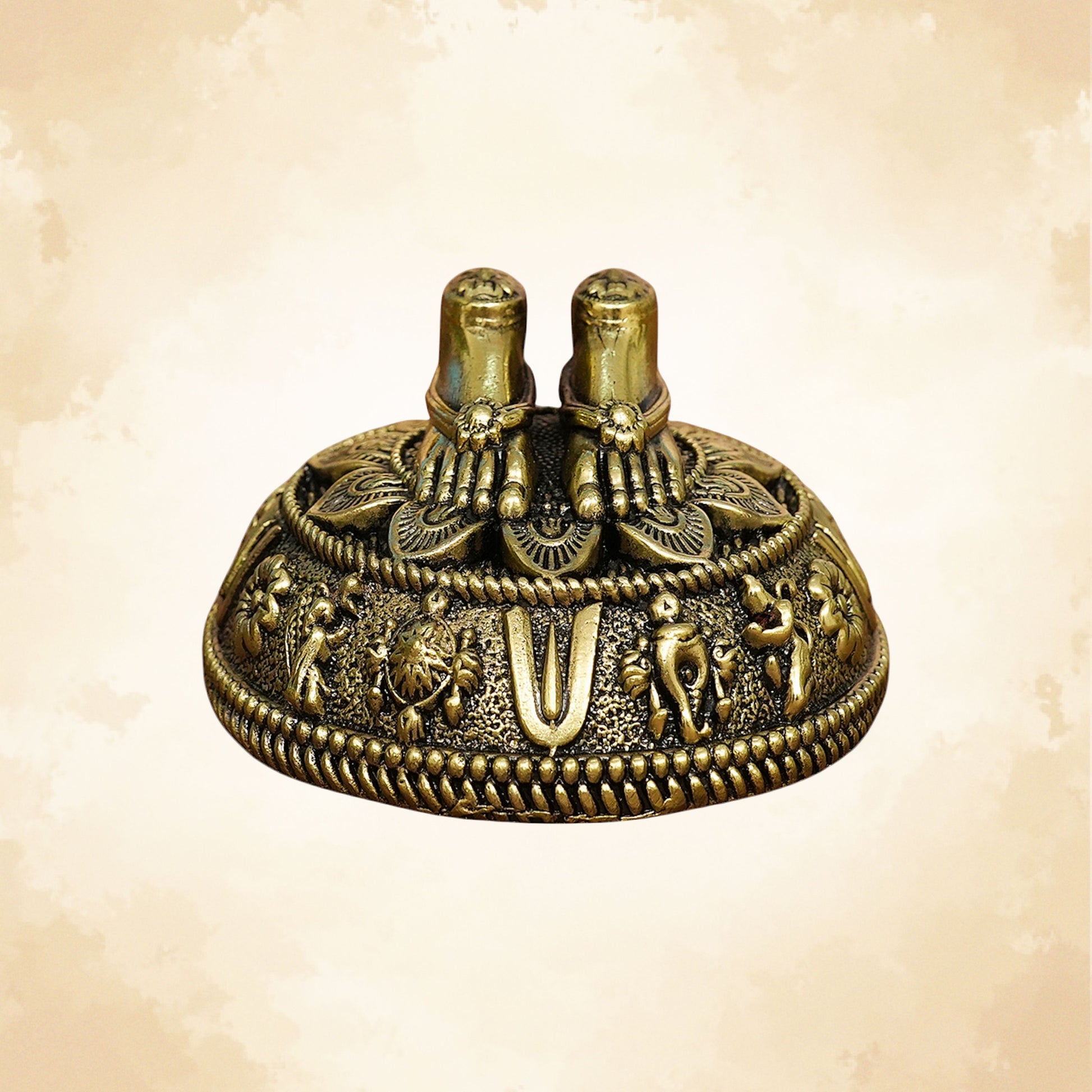 Handcrafted brass Charan Paduka placed on an ornate circular base with elephant and floral carvings.