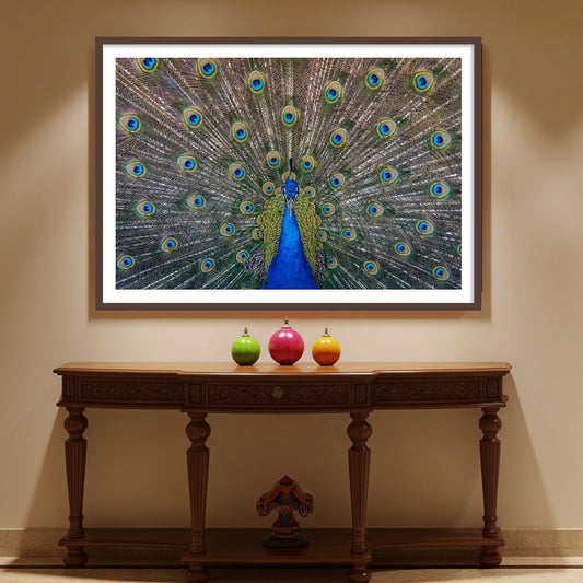 Decorative peacock vastu painting on a wall above a wooden console table with colorful apples and a vase.